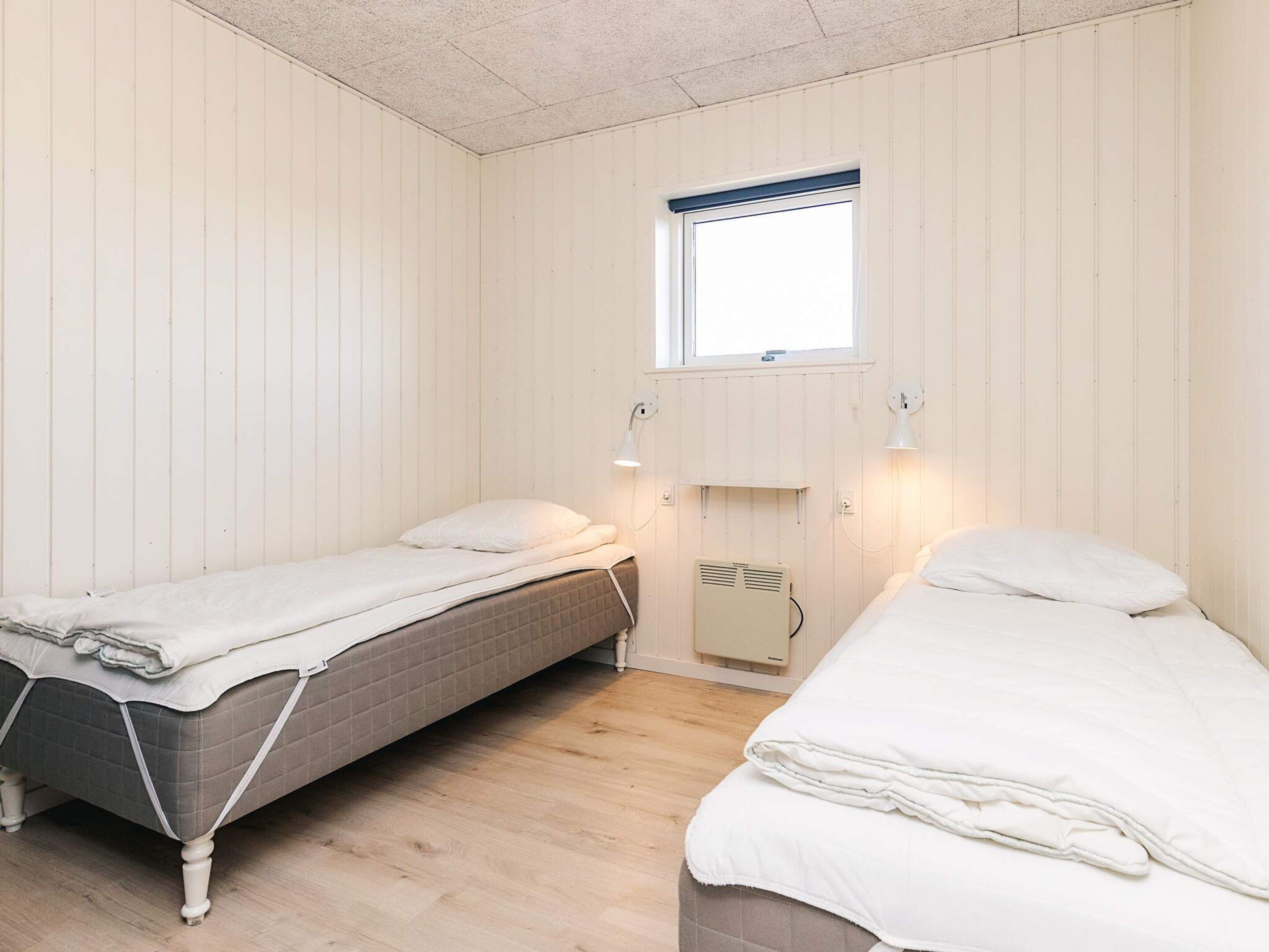 Et værelse med to enkeltsenge, et vindue og en fastgjort varmeblæser.