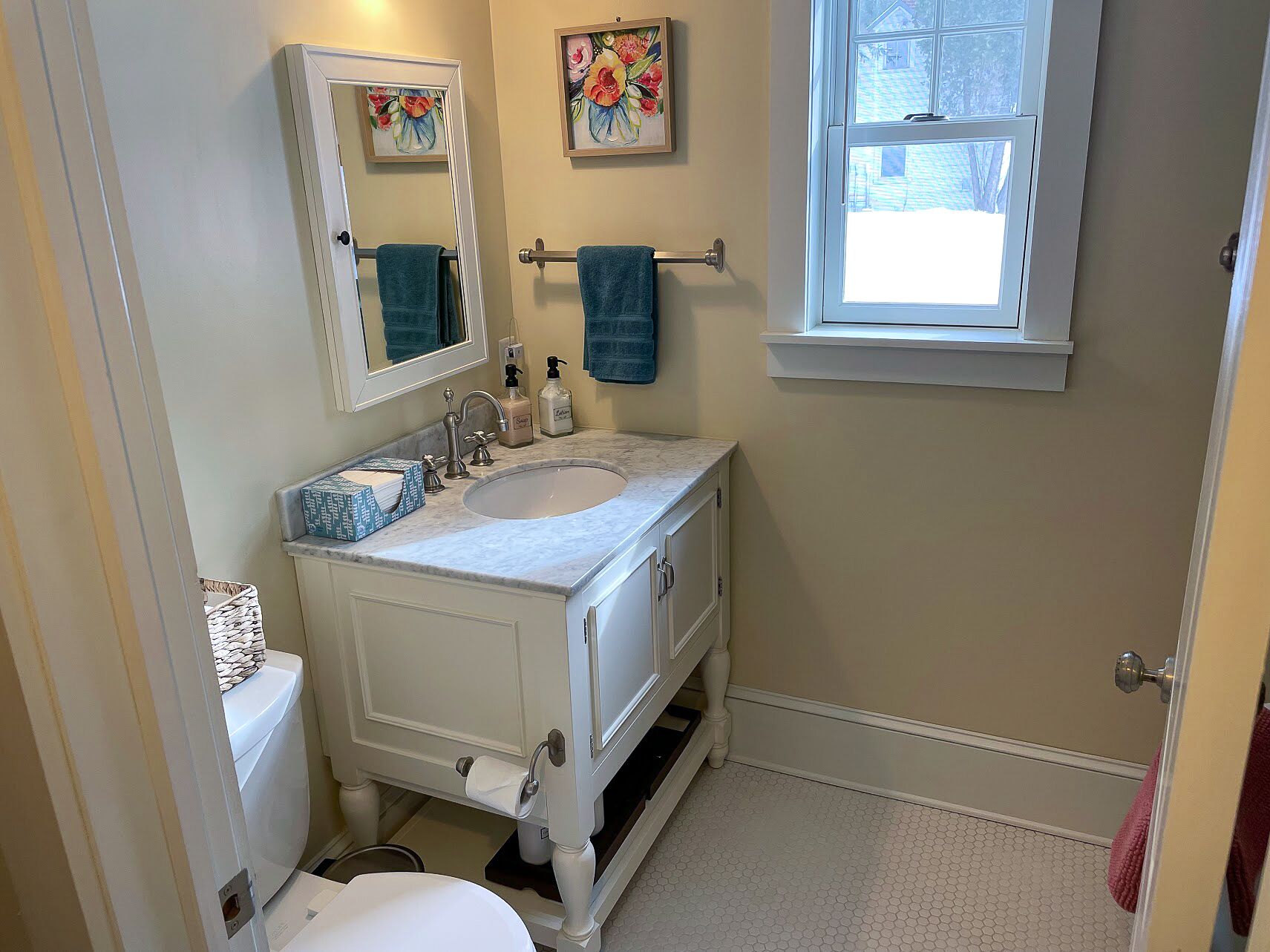 Un bagno con un mobile lavabo bianco, un lavandino, un water e una finestra.