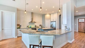 A modern kitchen with a large island, pendant lighting, and a stainless steel range hood. - Waterfront Lake Tawakoni Home w/ Fire Pit! (Quinlan)