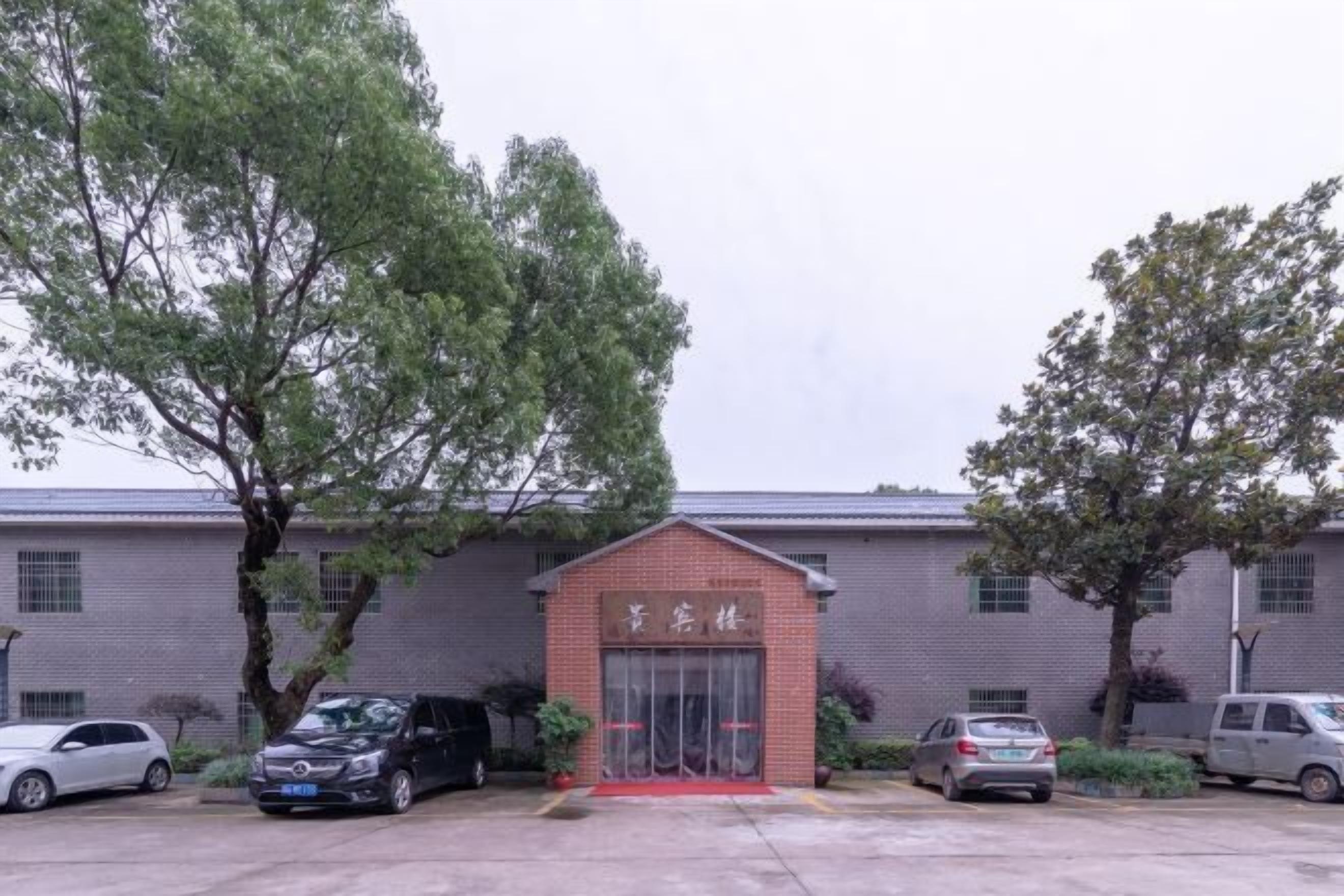 Un edificio con entrada de ladrillo rojo, alfombra roja y coches estacionados.