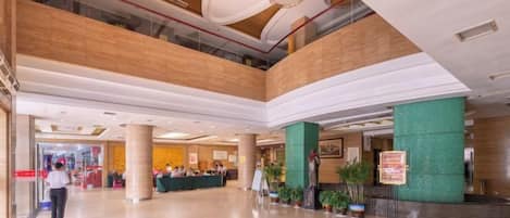 A spacious lobby with a high ceiling, multiple levels, and a central seating area.