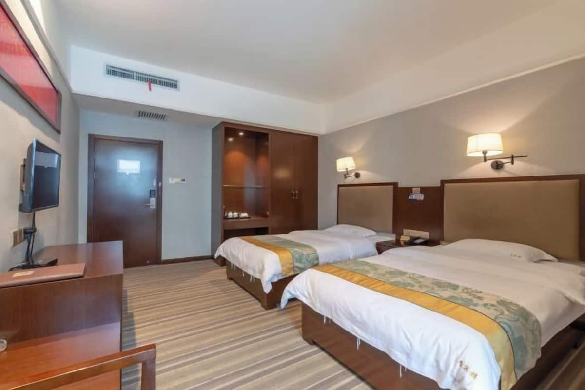 A hotel room with two beds, a desk, a TV, and a wardrobe.