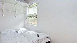 A single bed with a black frame, white bedding, and a remote control on it. - 5 Person Holiday Home in Ansager (Ansager)