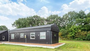 A modern, single-story building with a flat roof, large windows, and a wooden deck in front. - 5 Person Holiday Home in Ansager (Ansager)