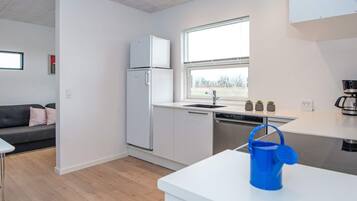 A modern kitchen with a refrigerator, dishwasher, and a window with a view.
