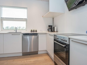 Een moderne keuken met roestvrijstalen apparatuur, een vaatwasser en een koffiezetapparaat.