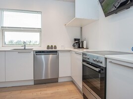 Una cocina moderna con electrodomésticos de acero inoxidable, lavavajillas y cafetera.