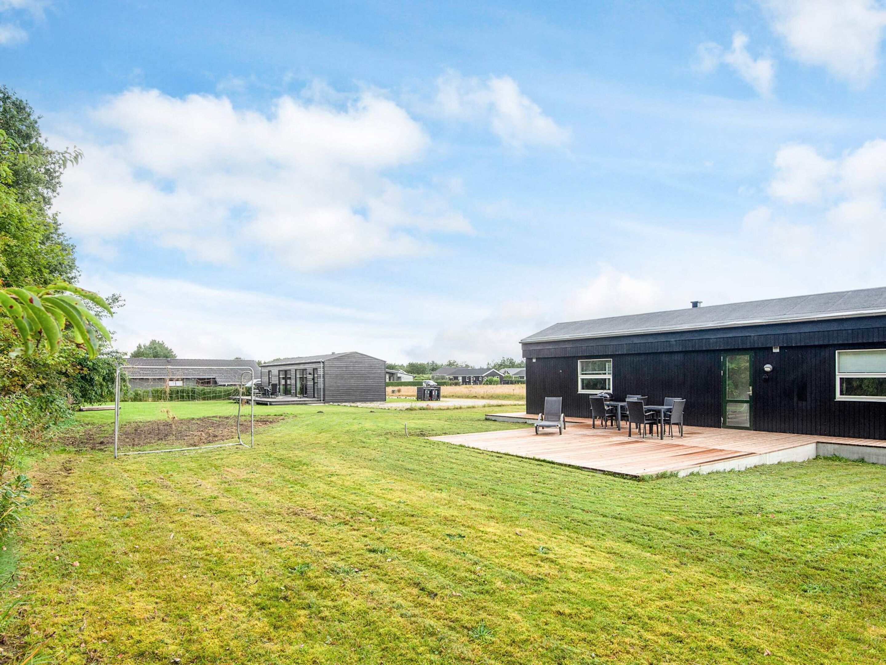 A modern house with a large backyard, a patio with outdoor furniture, and a well-maintained lawn.