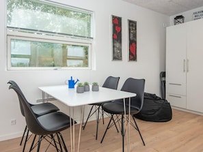 A room with a white table, four black chairs, a blue watering can, and three small potted plants. - 5 Person Holiday Home in Ansager (Ansager)