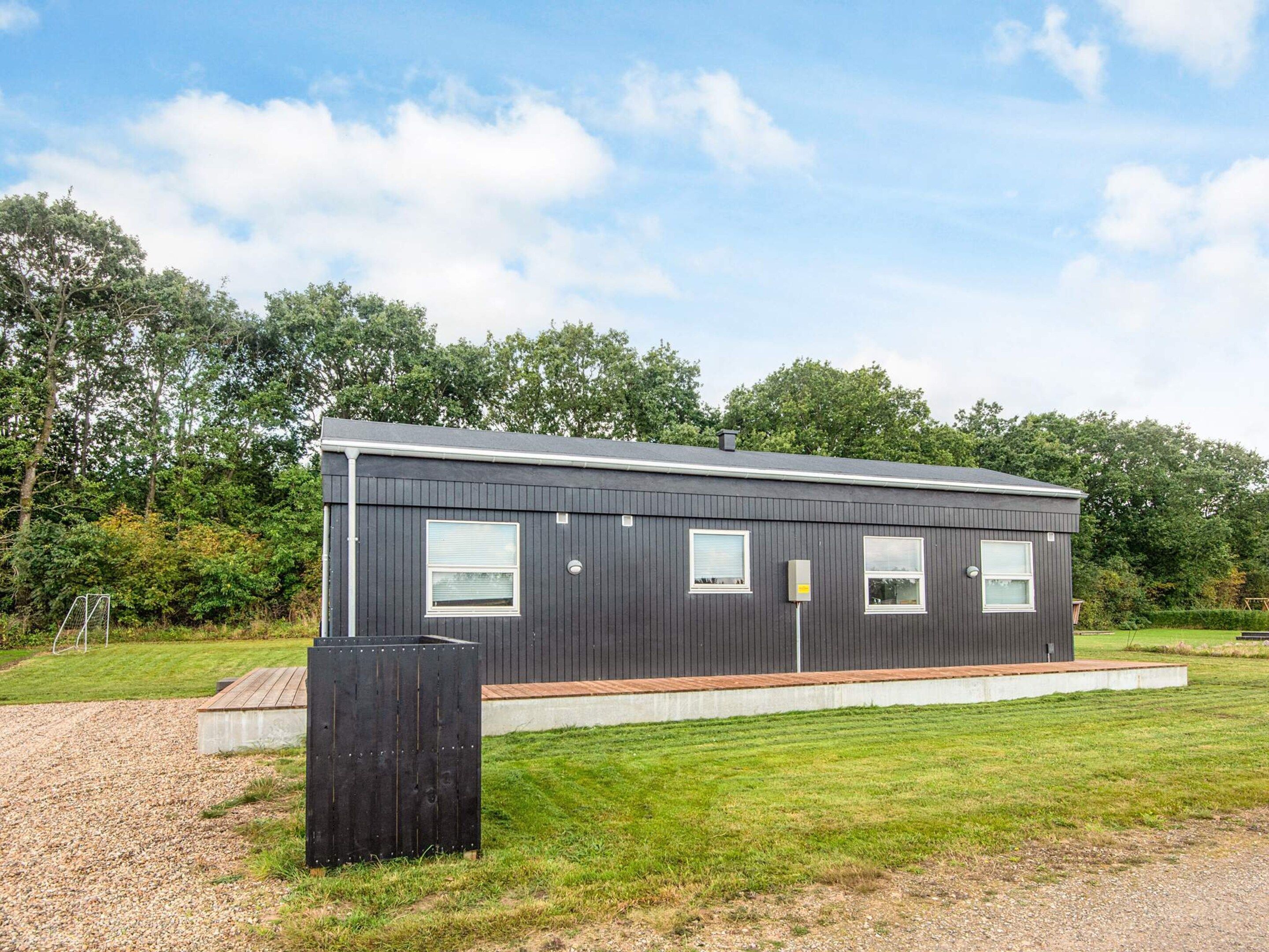 A modern, single-story building with a flat roof, large windows, and a concrete foundation.