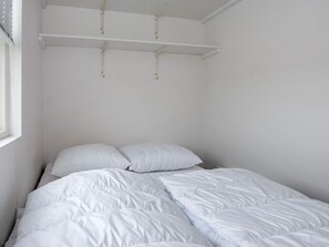 A single bed with white bedding in a room with white walls and a window on the left. - 5 Person Holiday Home in Ansager (Ansager)