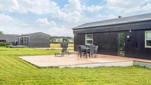 A modern building with a patio area featuring outdoor furniture. - 5 Person Holiday Home in Ansager (Ansager)