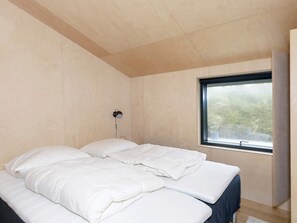 Quarto com cama, abajur e janela.