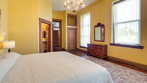 Un dormitorio con una cama grande, una araña, un tocador y una ventana con cortinas.