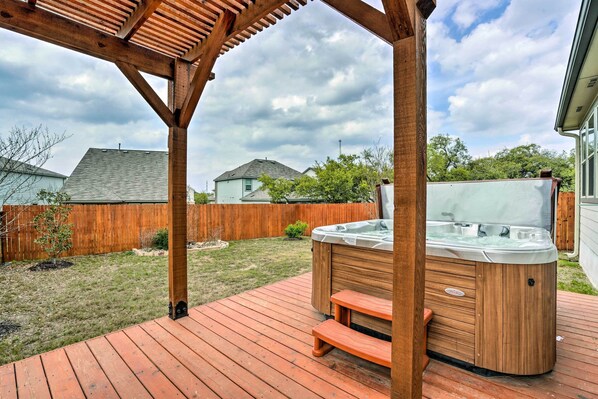 Una terraza de madera con jacuzzi y pérgola.
