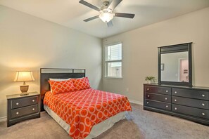 Un dormitorio con cama, mesitas de noche, cómoda, ventilador de techo y ventana.