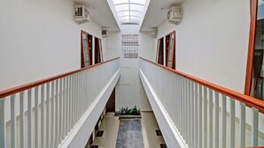 A corridor with a skylight, white railings, and air conditioning units. - Hotel O Madania Guesthouse Syariah (Mataram)