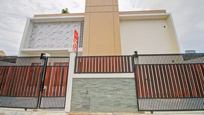 A modern building with a beige facade, a large window, and a closed shutter. - Hotel O Madania Guesthouse Syariah (Mataram)
