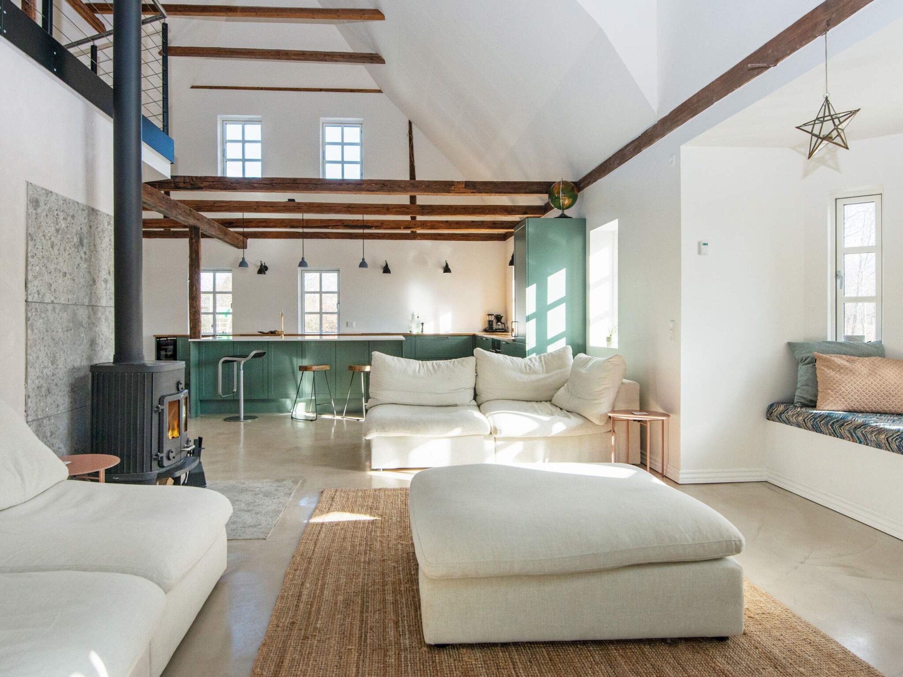 A spacious living area with a sofa, ottoman, and a fireplace.
