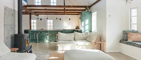 A spacious living area with a sofa, ottoman, and a fireplace.
