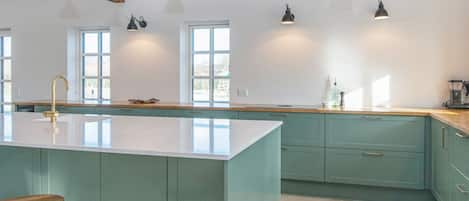 A kitchen with a central island, bar stools, pendant lighting, and wooden beams.