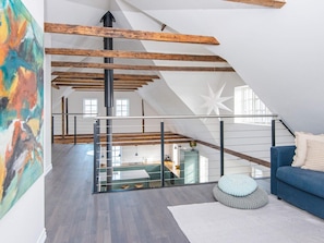 Relax in this spacious loft with a glass staircase, comfortable sofa, and abstract art.