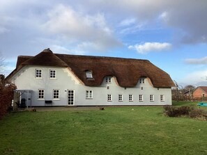 Un grand bâtiment blanc doté d’un toit de chaume et de nombreuses fenêtres.