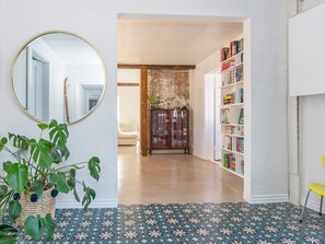 Un pasillo con un espejo, una planta en maceta, una estantería y un piso con diseño.