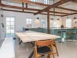 Une cuisine moderne dotée d’un îlot central, de poutres en bois et de luminaires suspendus.