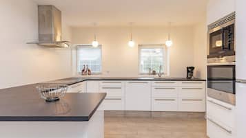 A modern kitchen with a central island, built-in oven, and pendant lighting.