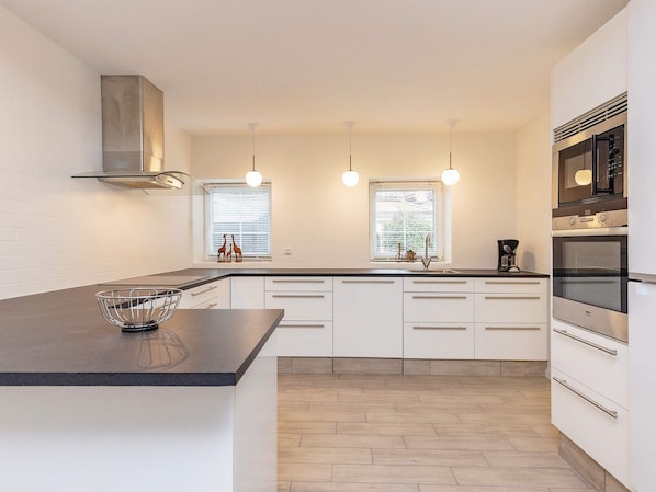 A modern kitchen with a central island, built-in oven, and pendant lighting.