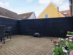 Un'area patio con recinzione nera, un barbecue e mobili da esterno.