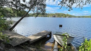 A wooden dock extending into a calm lake, surrounded by trees and vegetation.