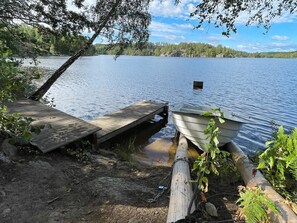 A wooden dock extending into a calm lake, surrounded by trees and vegetation.