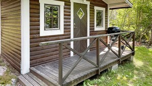 A small wooden cabin with a porch and two windows.