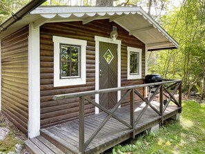 A small wooden cabin with a porch and two windows.