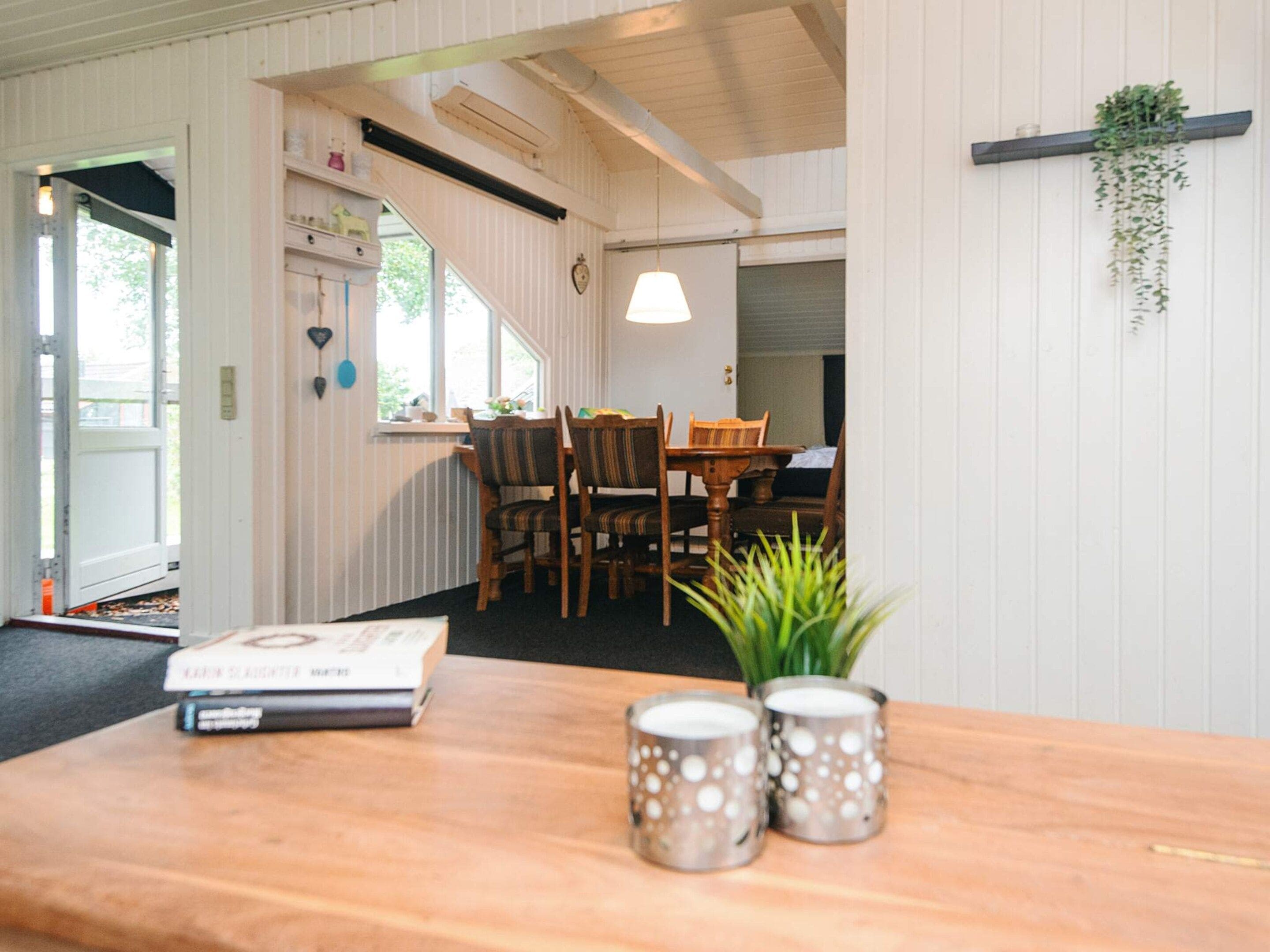 Een kamer met een houten tafel, stoelen, een hangplant en een raam.