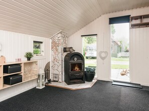 A room with a stone fireplace, a wooden shelf with glasses, and a door leading outside. - 4 Person Holiday Home in Hemmet (Hemmet)