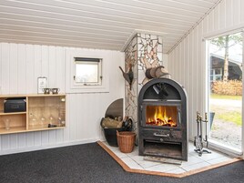 Una habitación con chimenea de piedra, una ventana, una estantería con vasos y una cesta.