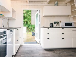 A compact kitchen with white cabinetry, a built-in microwave, and a coffee maker. - 4 Person Holiday Home in Hemmet (Hemmet)