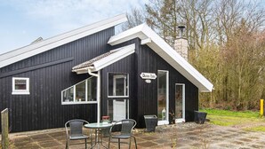 A black building with a white roof, a chimney, and a sign reading 'Damm-Ida'. There are two chairs and a table outside. - 4 Person Holiday Home in Hemmet (Hemmet)