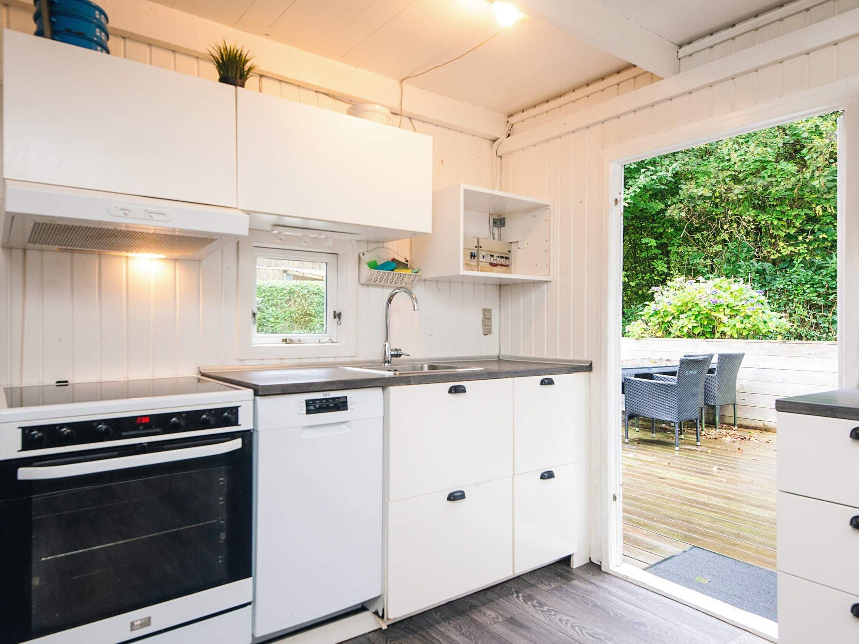 A compact kitchen with white cabinets, a built-in oven, and a window.