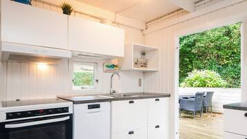 A compact kitchen with white cabinets, a built-in oven, and a window.
