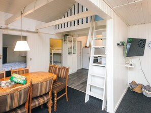 A compact room with a dining table, chairs, a bunk bed, a kitchen area, and a TV mounted on the wall. - 4 Person Holiday Home in Hemmet (Hemmet)