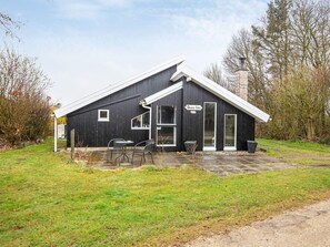 En svart byggnad med ett vitt tak, en skylt med texten ”Dammtor”, och två bord utomhus.