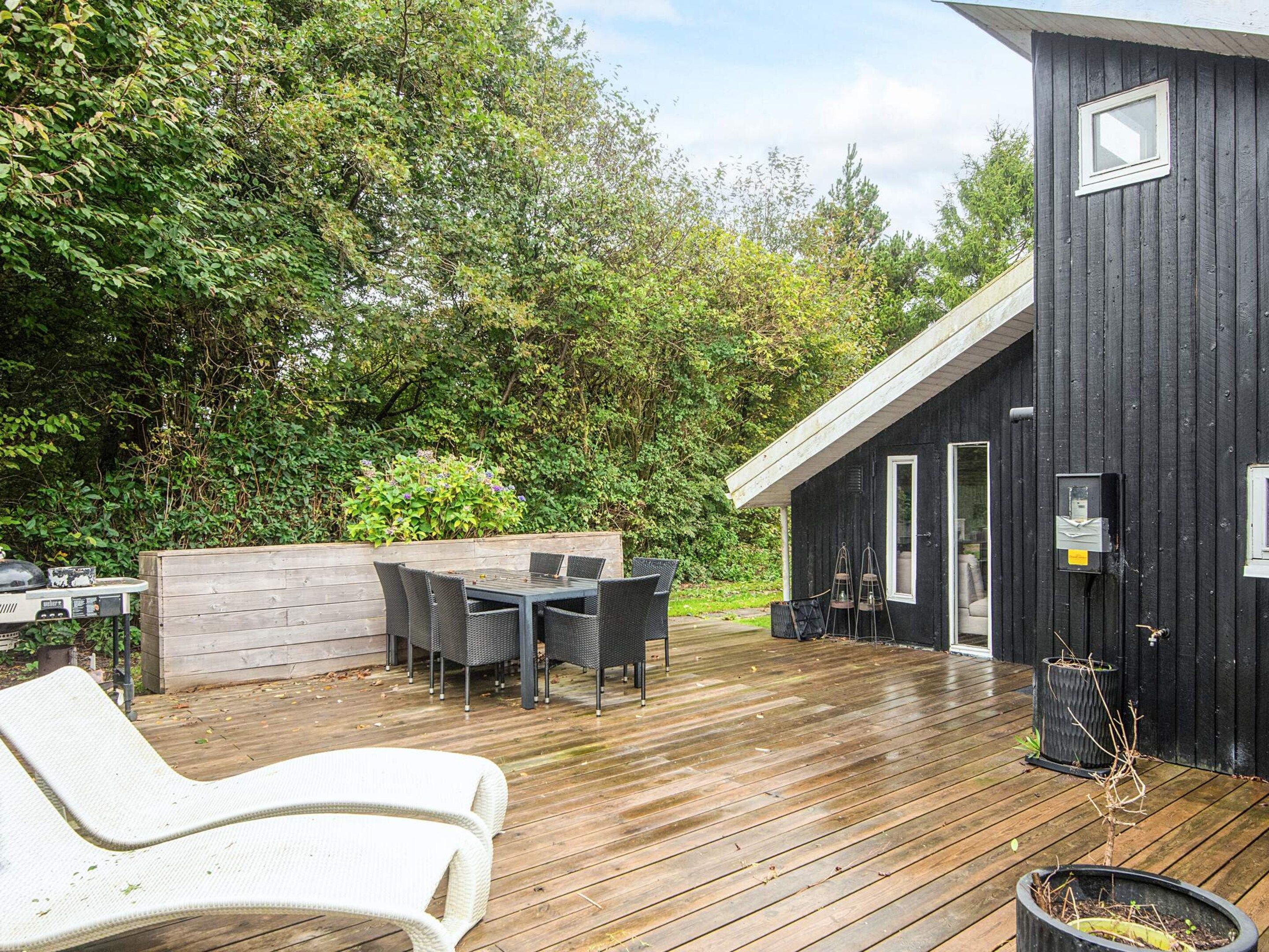 Une terrasse en bois avec des meubles d’extérieur, une petite table et une chaise.