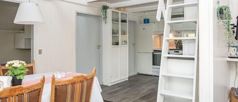 A compact kitchen with white cabinetry, a refrigerator, and a microwave.