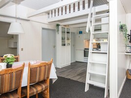 Una cocina compacta con muebles blancos, un refrigerador y un microondas.