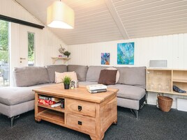 Una sala acogedora con un sofá modular, una mesa de centro de madera y una estantería.