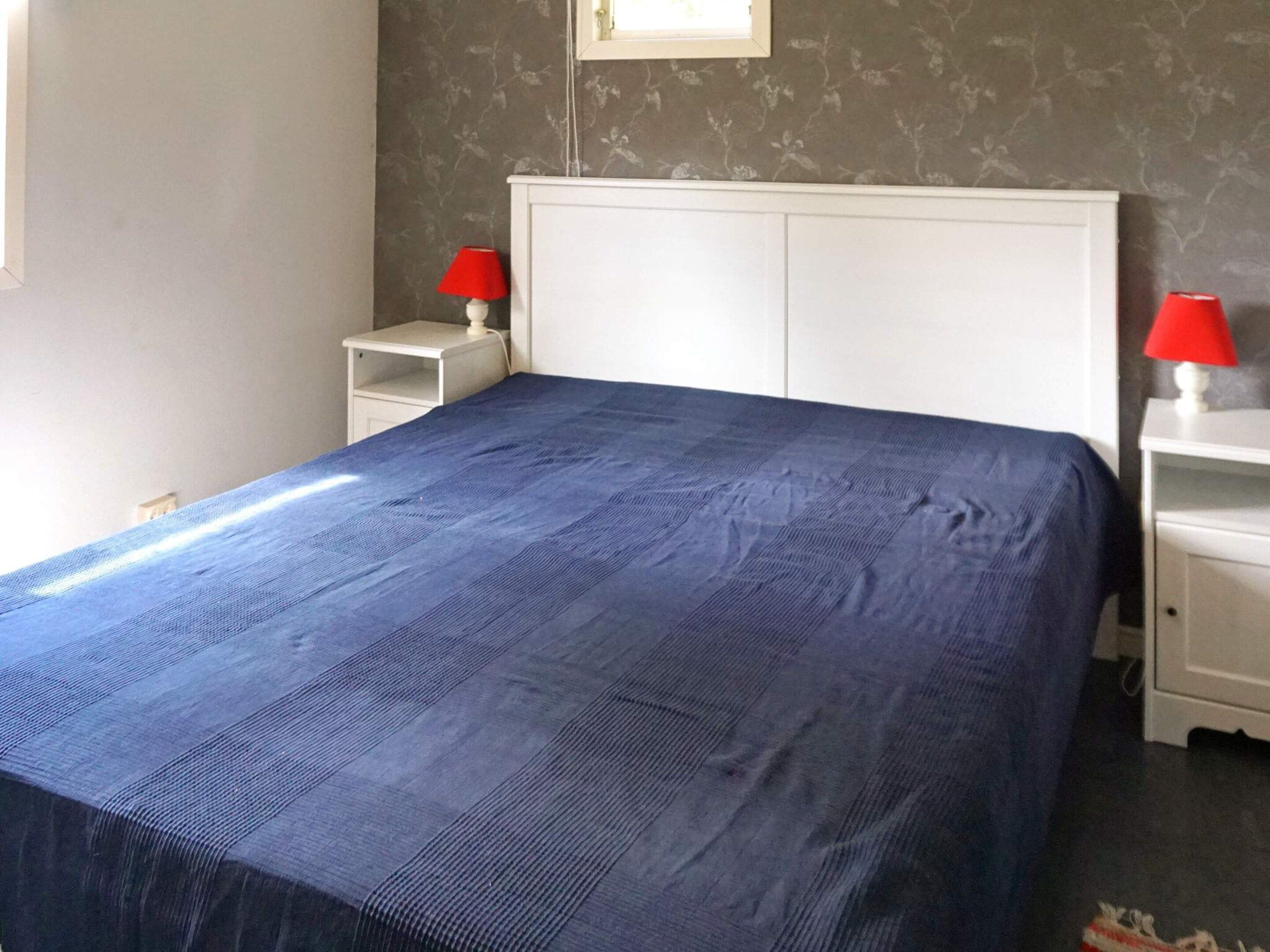 A bedroom with a large bed, two bedside tables, and a headboard.